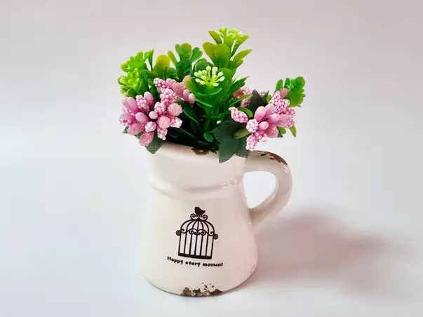 vas ceramic alb cu plante artificiale verzi si roz